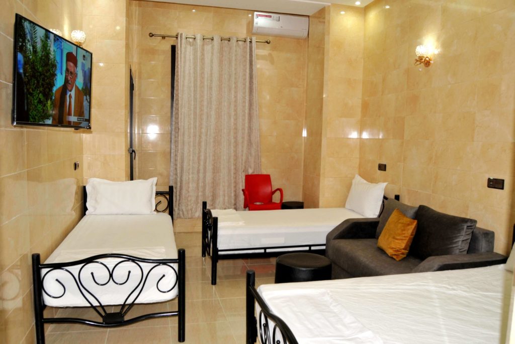 Chambre d'hotel Marrakech composée de 1 lit double et 2 lits simple pour 4 personnes avec salle de bain privée, TV avec satellite, Wifi, salon avec des canapés